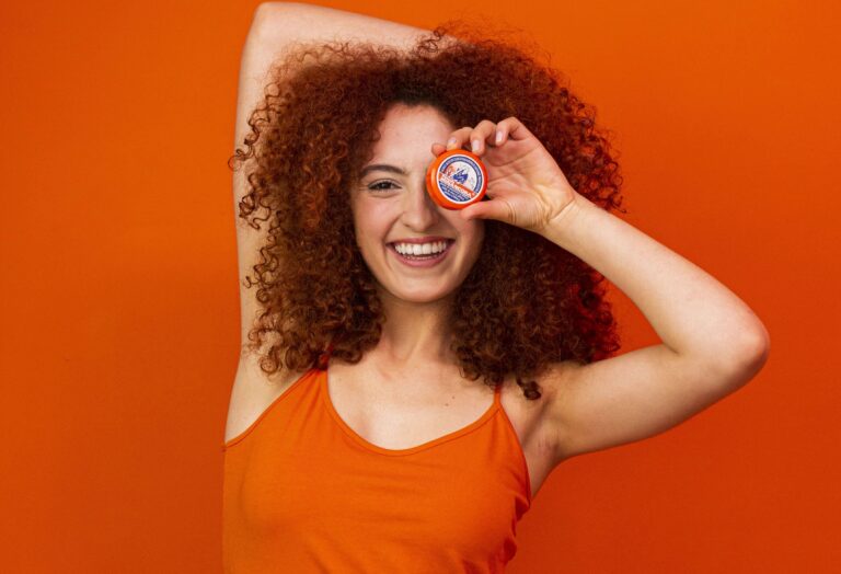 Mulher feliz segurando a Pomada Minancora! Confira dicas de cuidados com a pele no nosso blog.