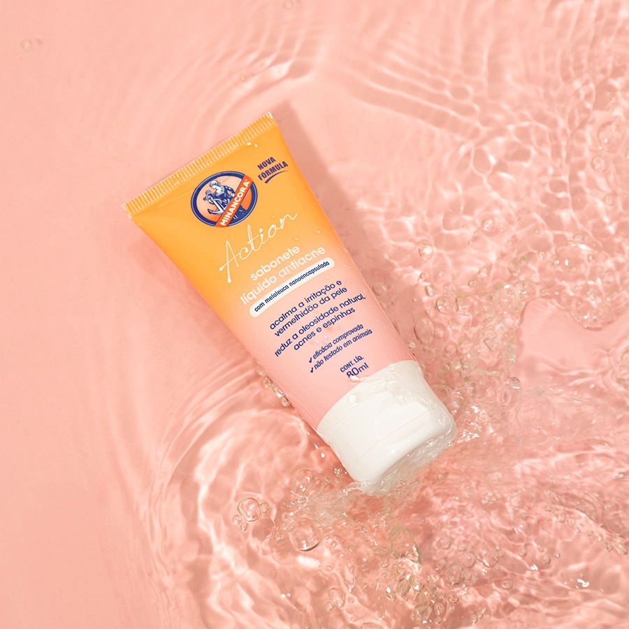 Embalagem do Sabonete Líquido Antiacne Minancora em frente a um fundo rosa claro com água.