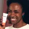 Pessoa sorridente segurando um produto facial, promovendo cuidados com a pele e skincare antissinais.