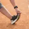 Pessoa realizando alongamento em pista de corrida, destacando cuidados com o pé de corredor para evitar bolhas, odores e rachaduras.